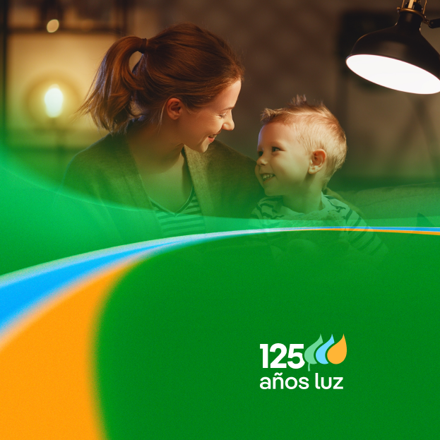 Una madre y su hijo se miran sonriendo, mientras una lámpara ilumina la escena en un ambiente cálido. Se destaca el logo de "125 años luz".