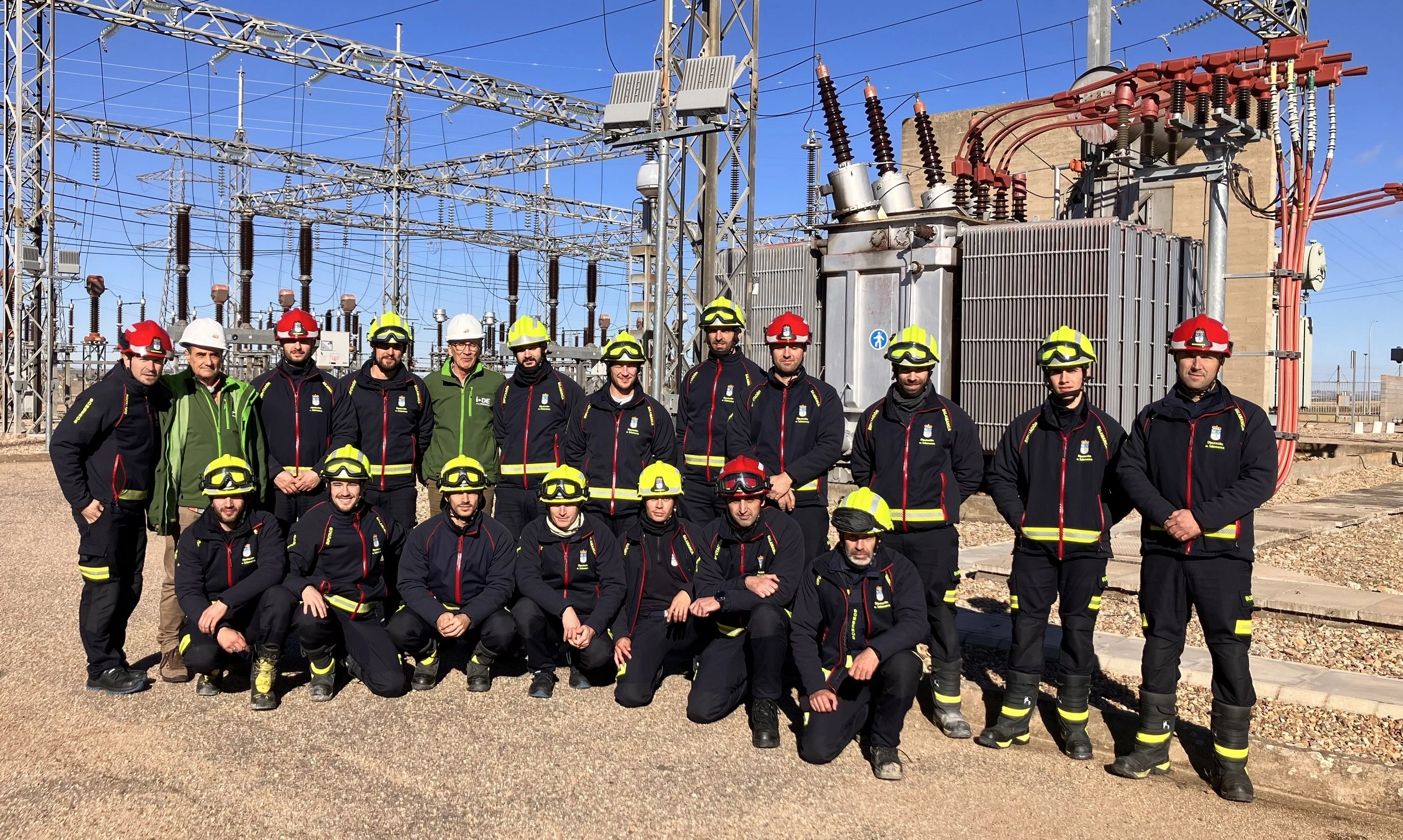 Grupo de bomberos en una subestación eléctrica, usando cascos y uniformes de seguridad