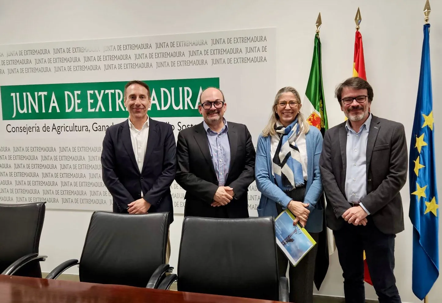 Meeting at the Junta de Extremadura with i-DE representatives, posing in front of the flags of the region, Spain, and the European Union.