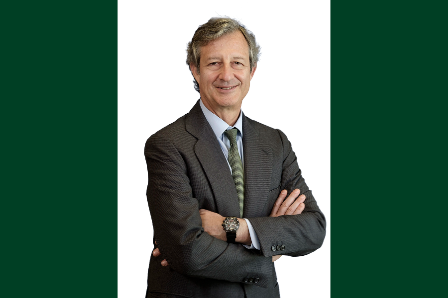 Portrait of an executive in suit with arms crossed on a neutral white and green background.