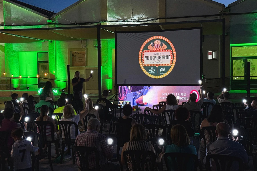 Público asistiendo a una proyección de cine al aire libre durante el Festival de Microcine de Verano, frente a una pantalla con el logotipo del evento.