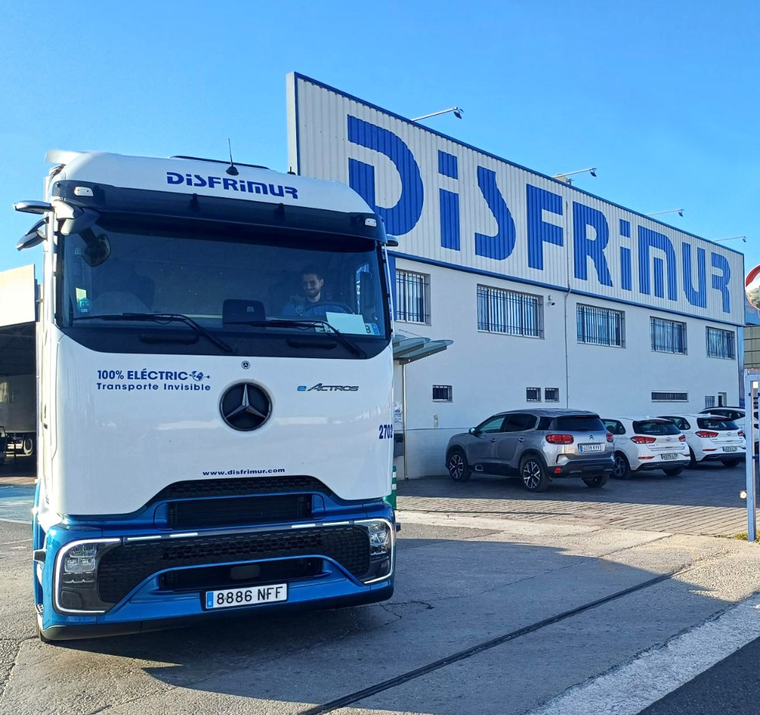 Un camión eléctrico Mercedes eActros con el logo de Disfrimur estacionado frente al edificio de la empresa.