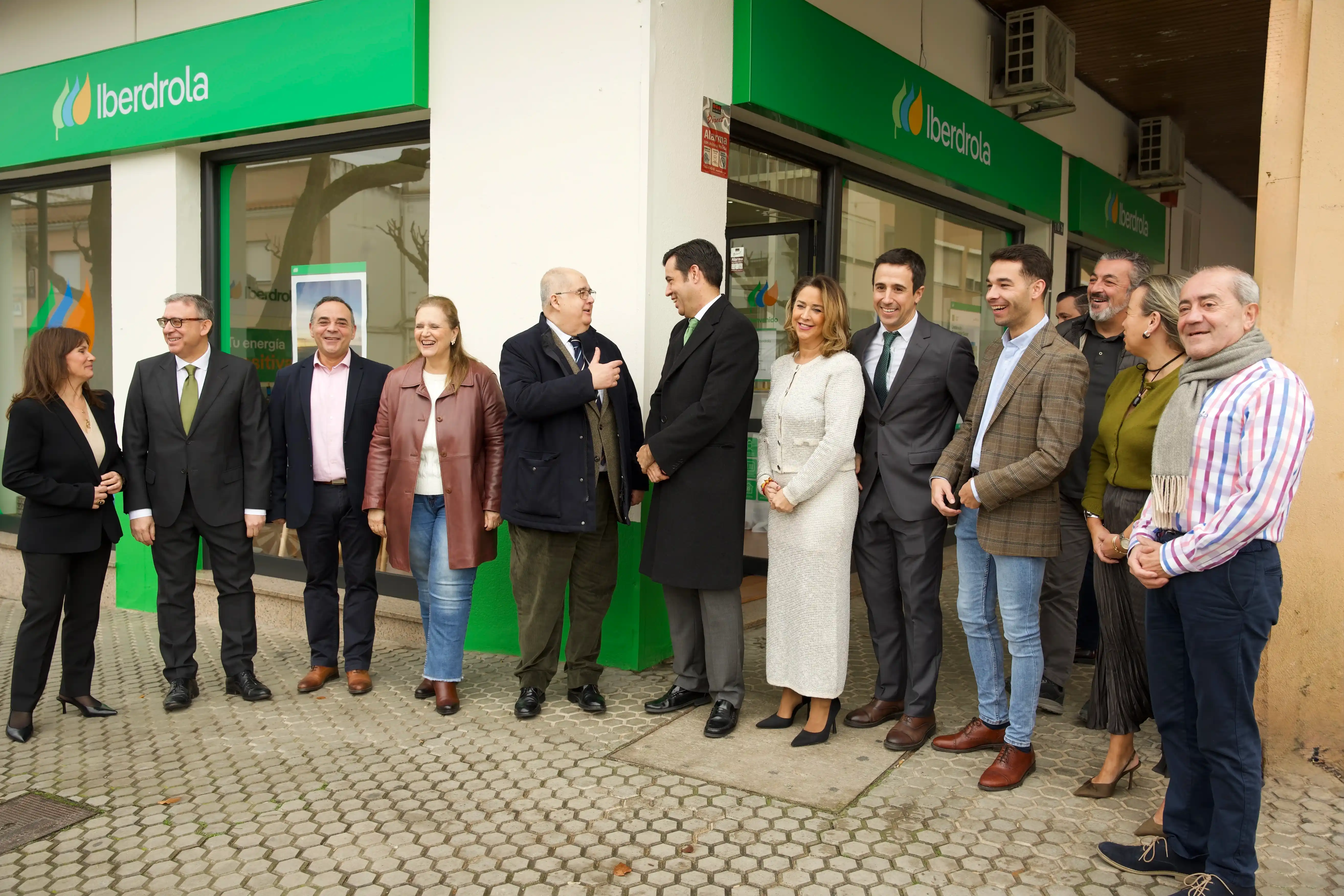 Grupo de personas posando frente a una tienda de Iberdrola, con la fachada y el logo de la empresa visible.