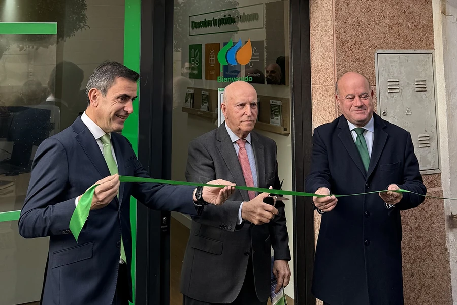 Three people inaugurate an Iberdrola office by cutting a green ribbon at the entrance.