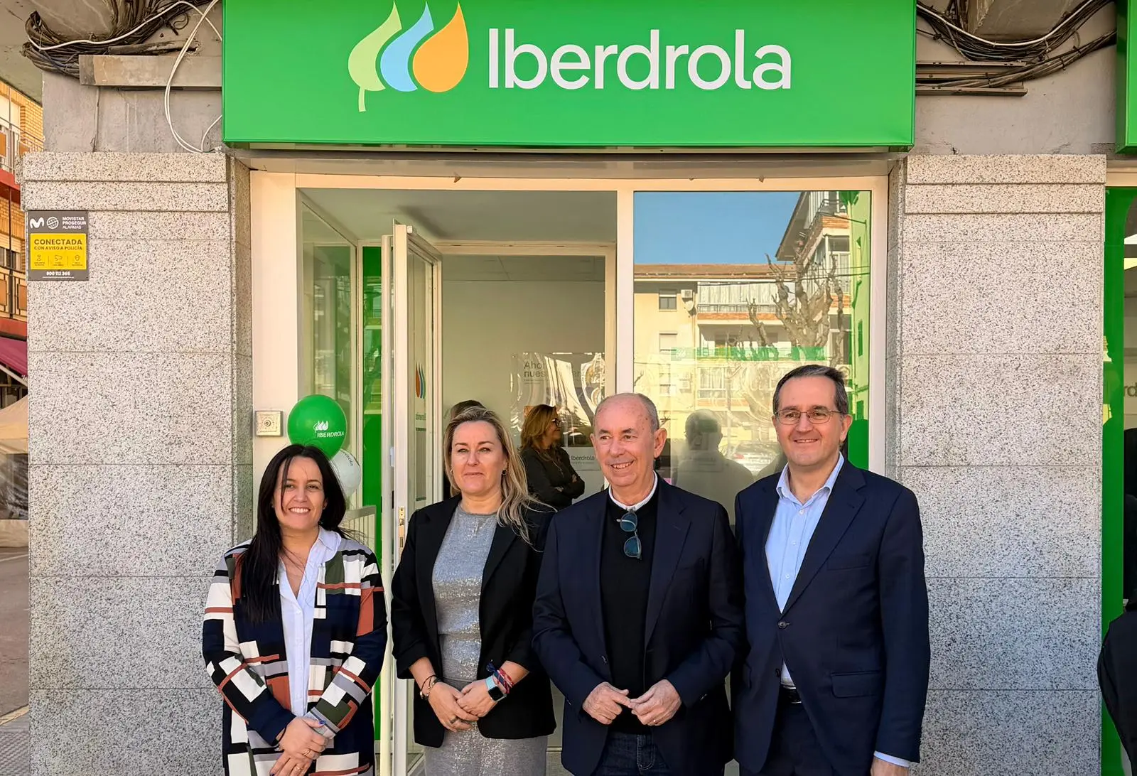 Four people are posing in front of an Iberdrola store in Massanassa, with the company’s sign visible at the top of the image.