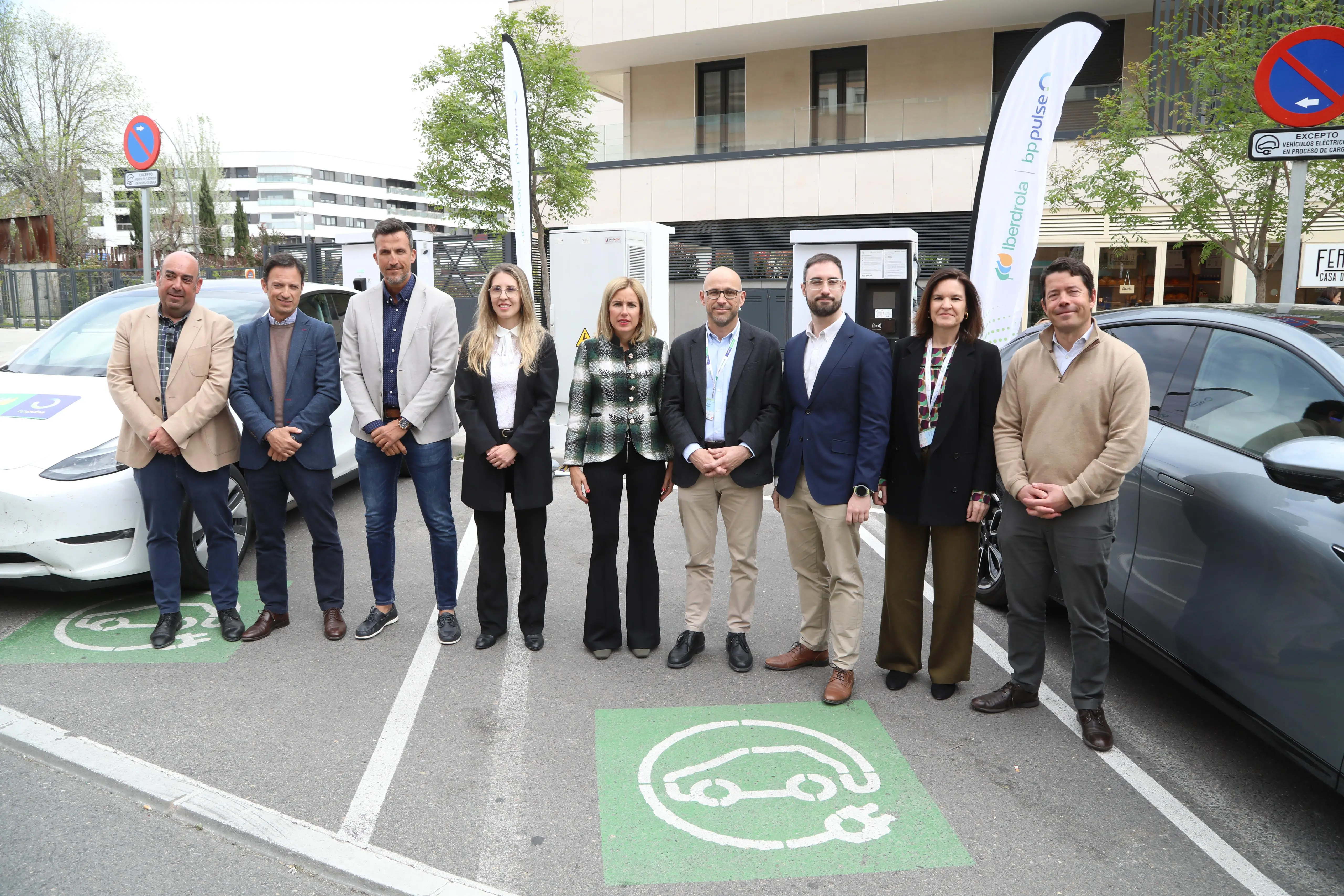 Grupo de personas posando frente a un punto de carga para vehículos eléctricos en Alcobendas, con el logo de Iberdrola y bp pulse en el fondo.