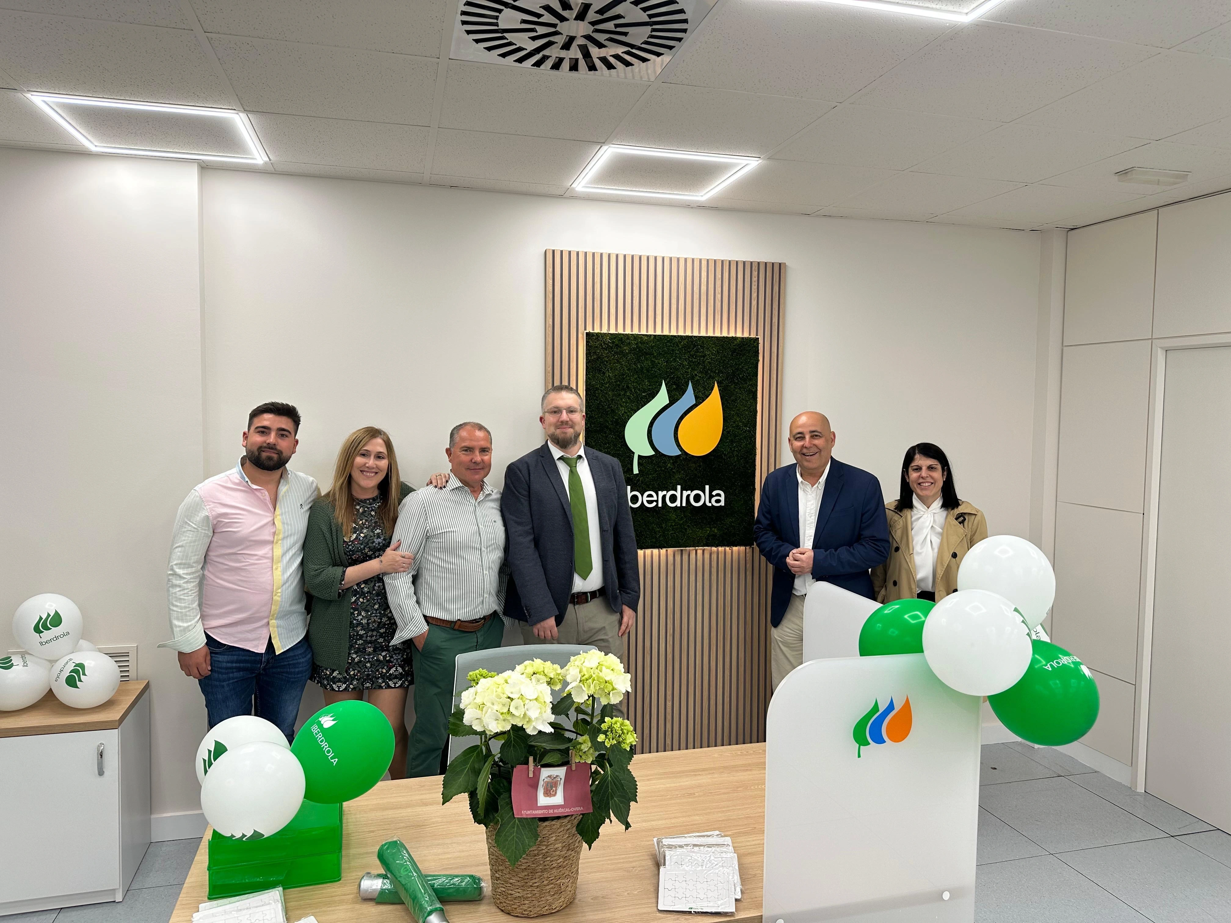 Team posing in an Iberdrola office next to the corporate logo and inauguration decorative elements.