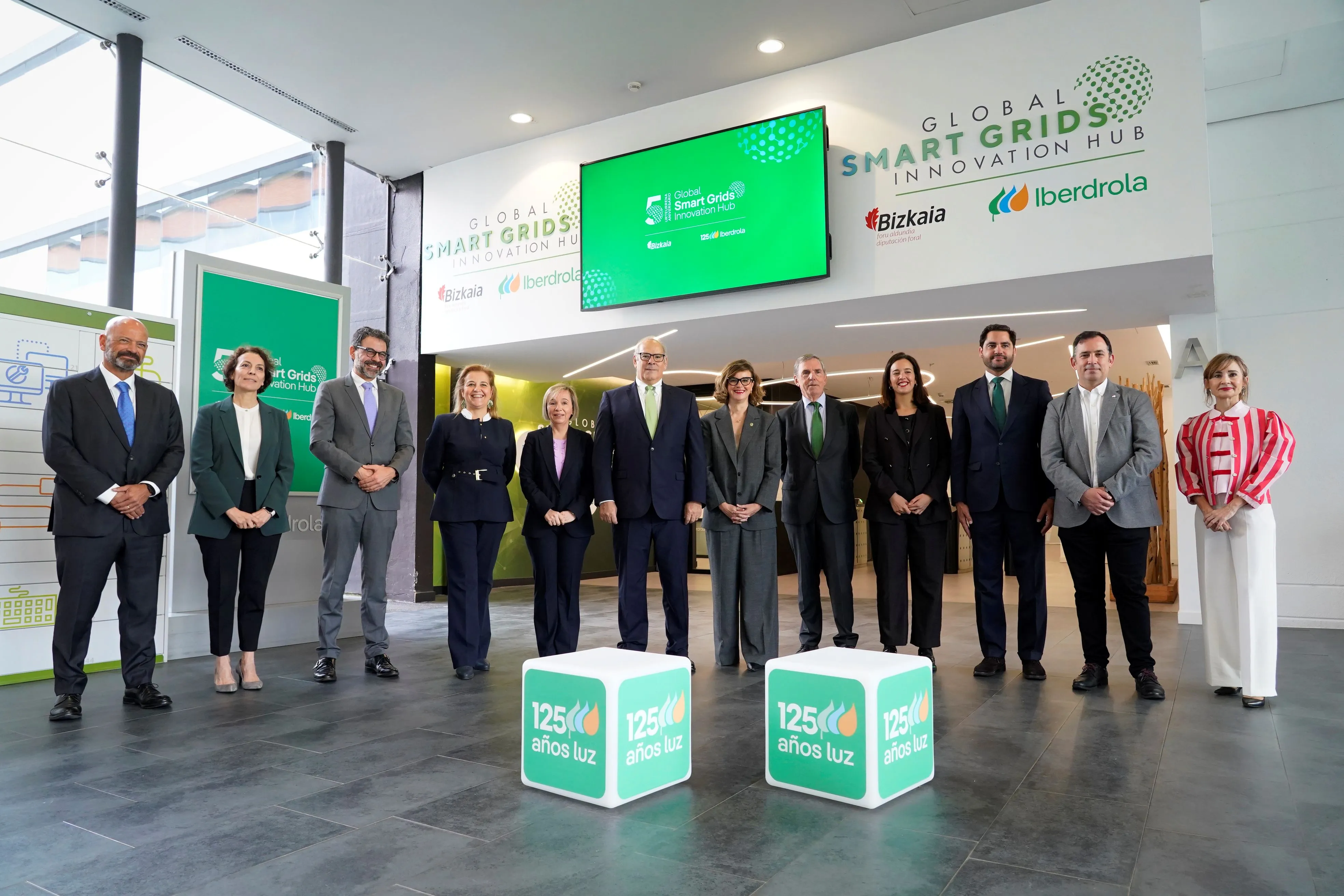 Grupo de personas posando durante el aniversario del Global Smart Grids Innovation Hub, con el logotipo de Iberdrola y Bizkaia visible en el fondo.