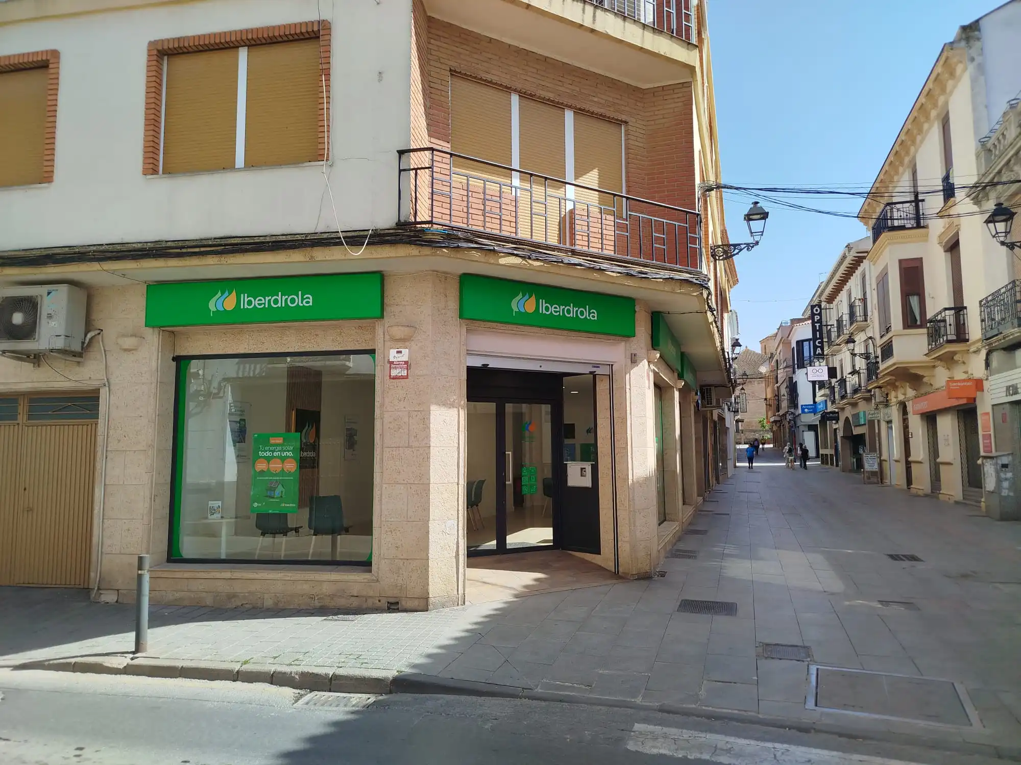 Punto de atención de Iberdrola en una esquina urbana, con fachada verde y acceso desde una calle peatonal.