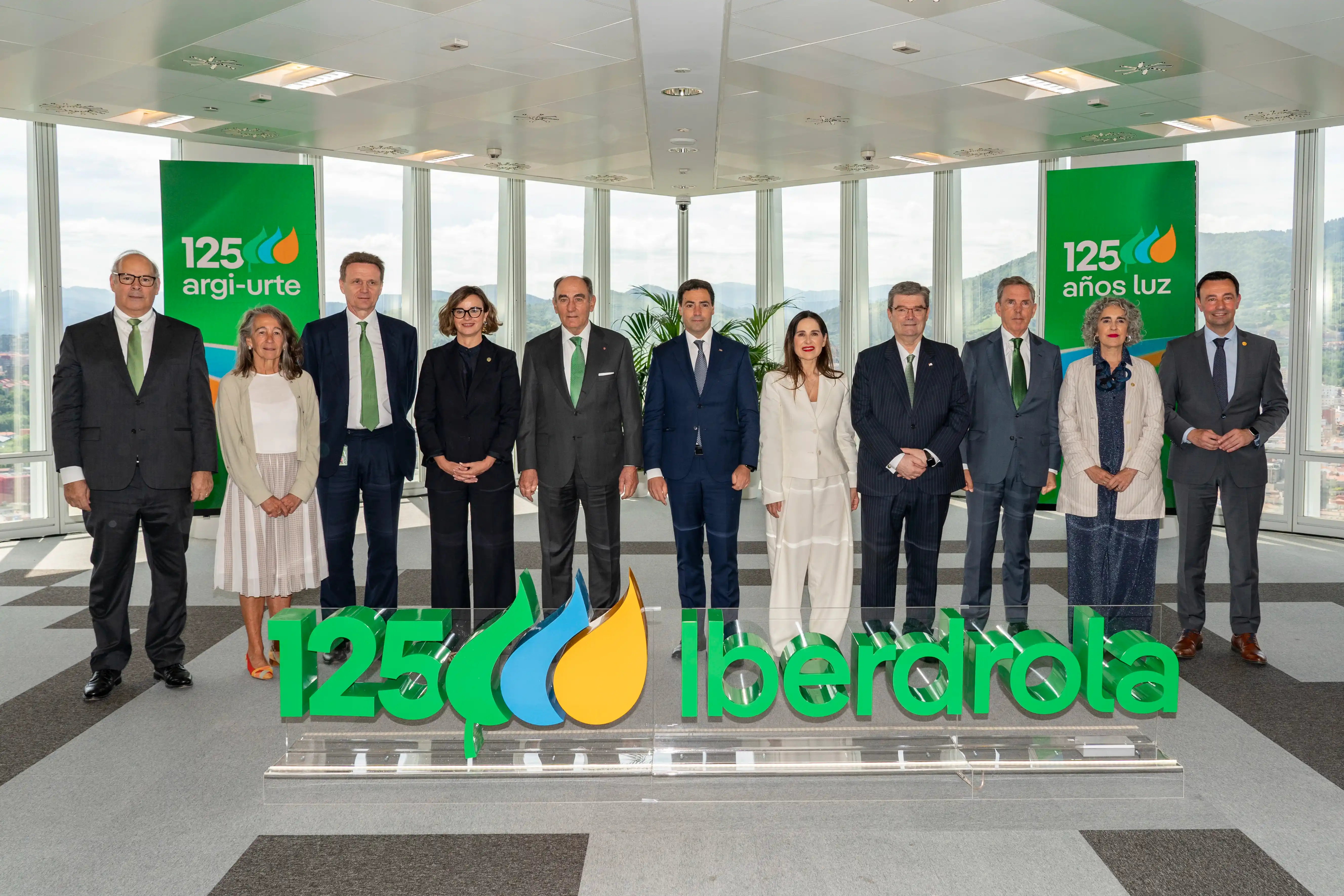 Grupo de directivos y ejecutivos posando frente a un cartel que celebra los 125 años de Iberdrola en Bilbao.