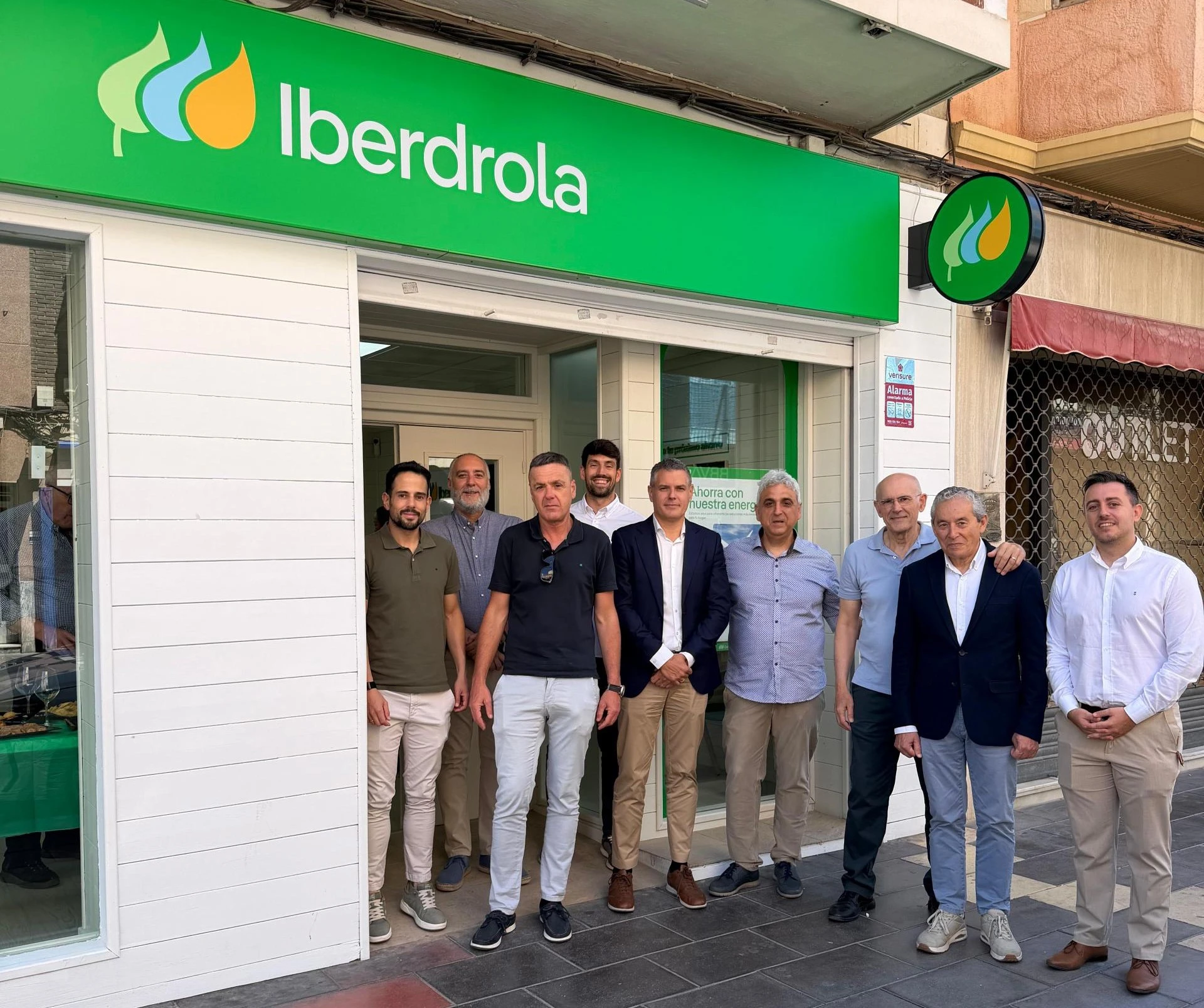 Group of people standing in front of an Iberdrola customer service office in Callosa de Segura, with green signage above the entrance.