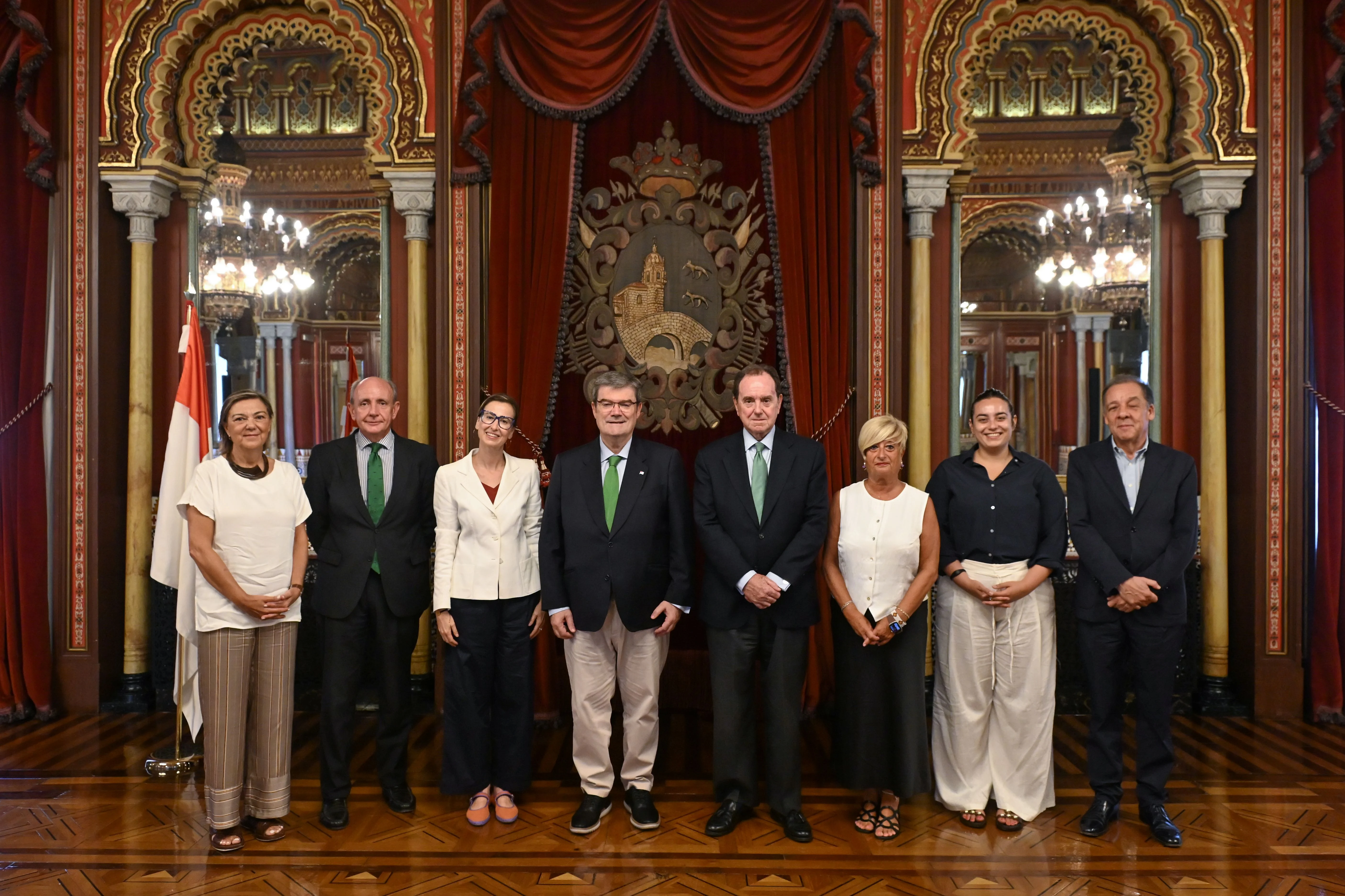 Grupo de personas posando en un acto institucional en un salón histórico con decoración oficial.