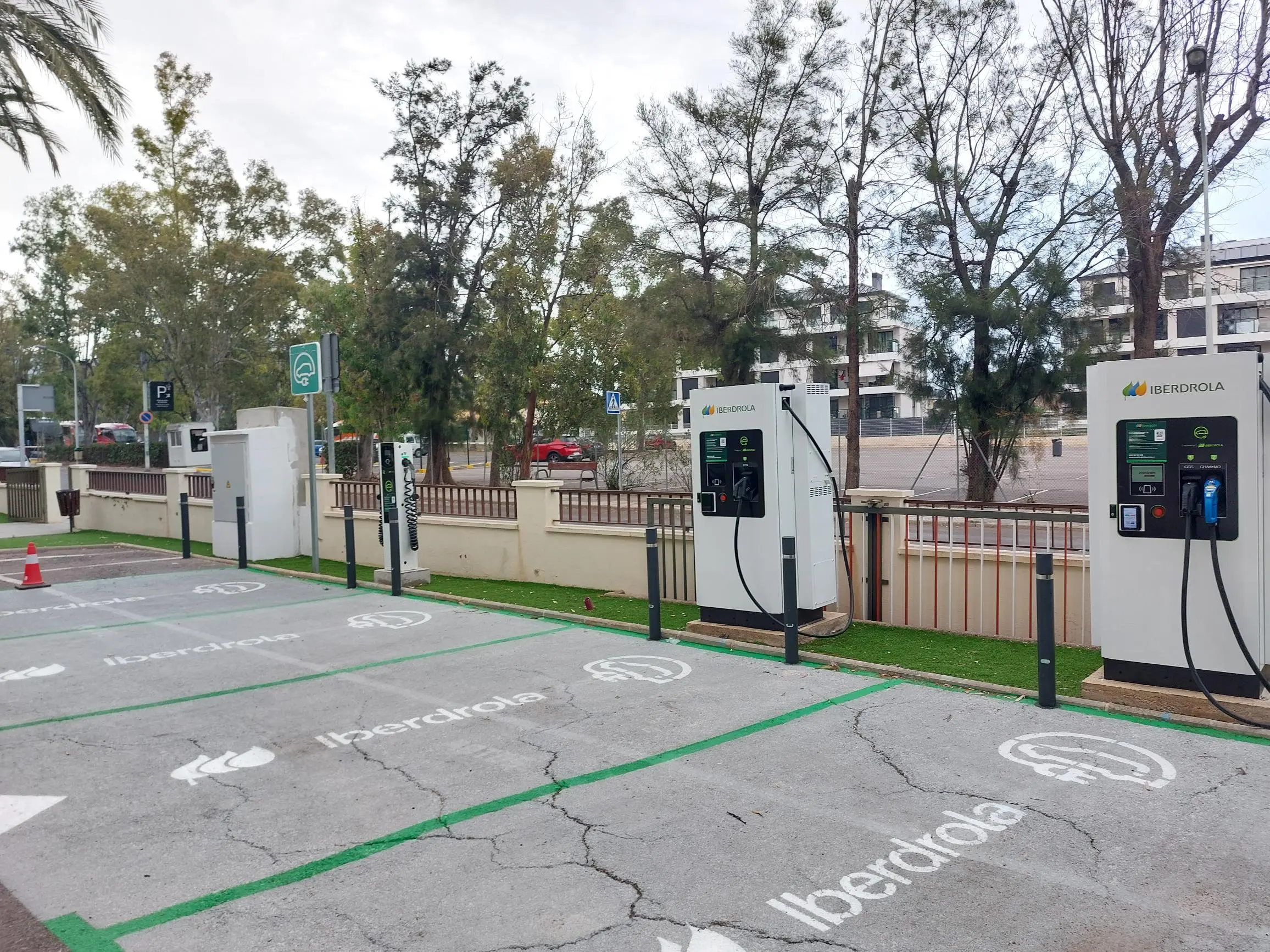 Estación de recarga para vehículos eléctricos de Iberdrola con varios puntos de carga en un aparcamiento al aire libre.