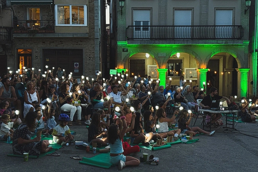 Público asistiendo a un evento nocturno con luces sostenibles en una plaza urbana.