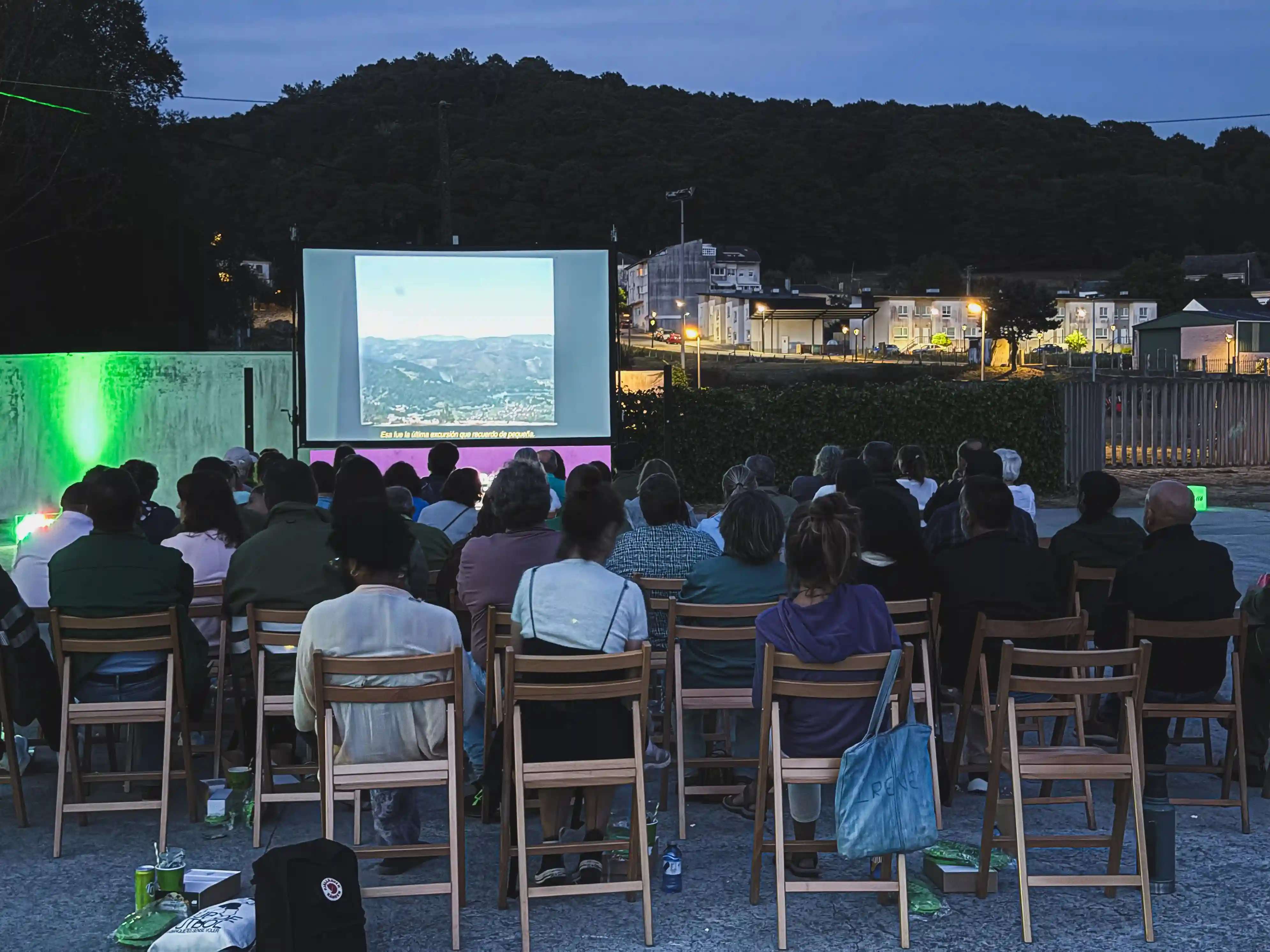 Audience attending an outdoor audiovisual screening at dusk