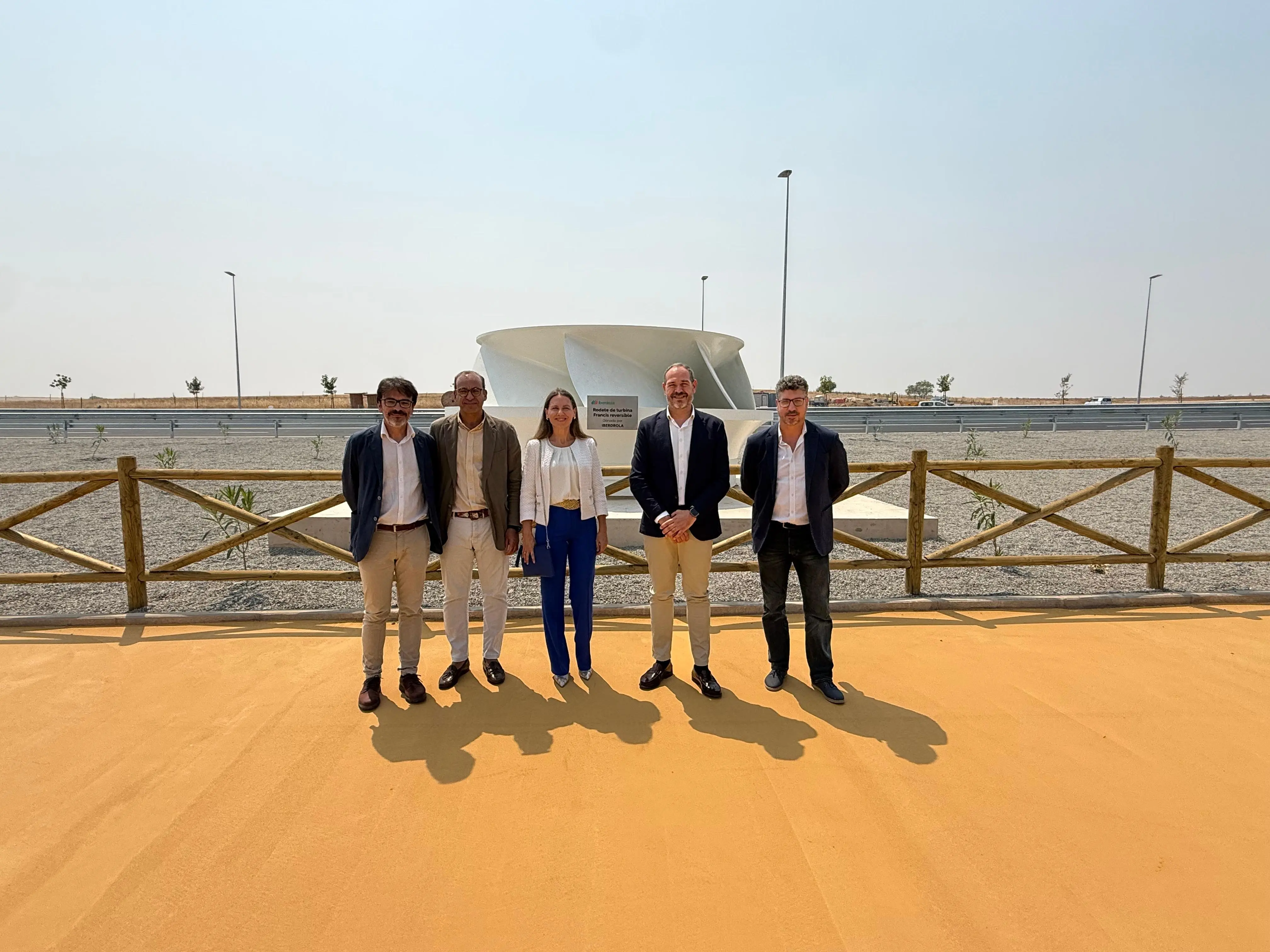 Cinco personas posan junto a una instalación de energía renovable en una zona exterior industrial.