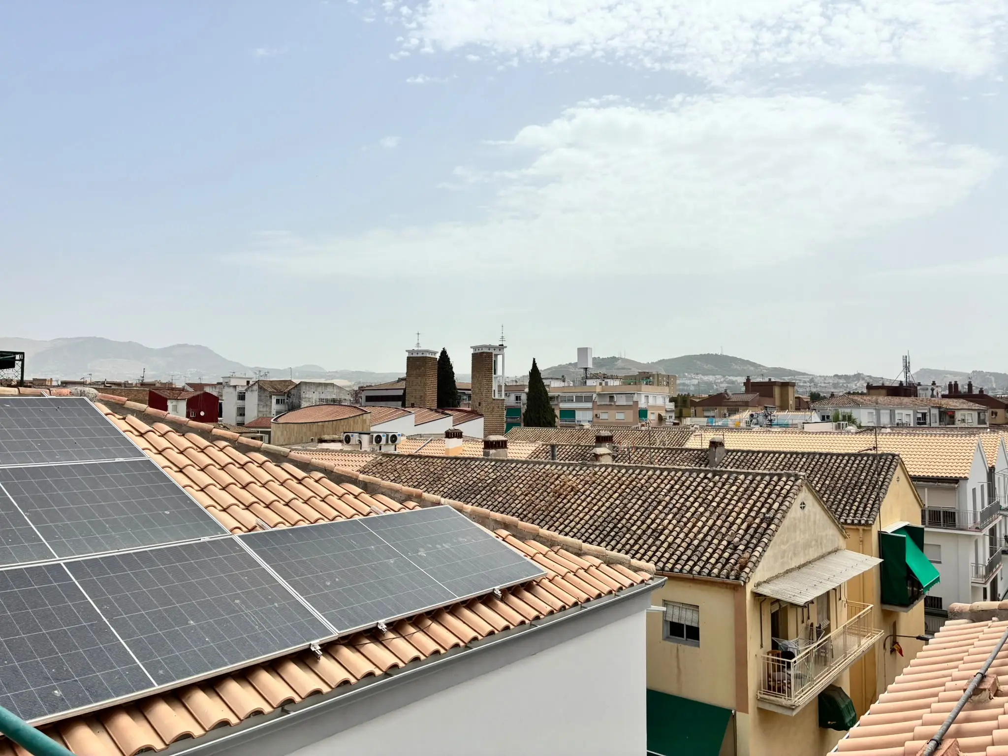 Paneles solares instalados en la cubierta de un edificio residencial en un entorno urbano, como ejemplo de rehabilitación energética.