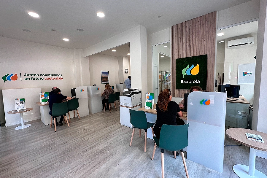 Oficina de atención de Iberdrola con clientes y personal en puestos de asesoramiento.