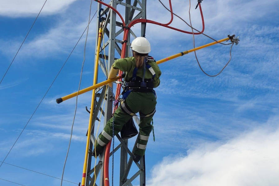 Técnica de trabajos eléctricos en altura realiza labores de mantenimiento en una torre de distribución eléctrica.