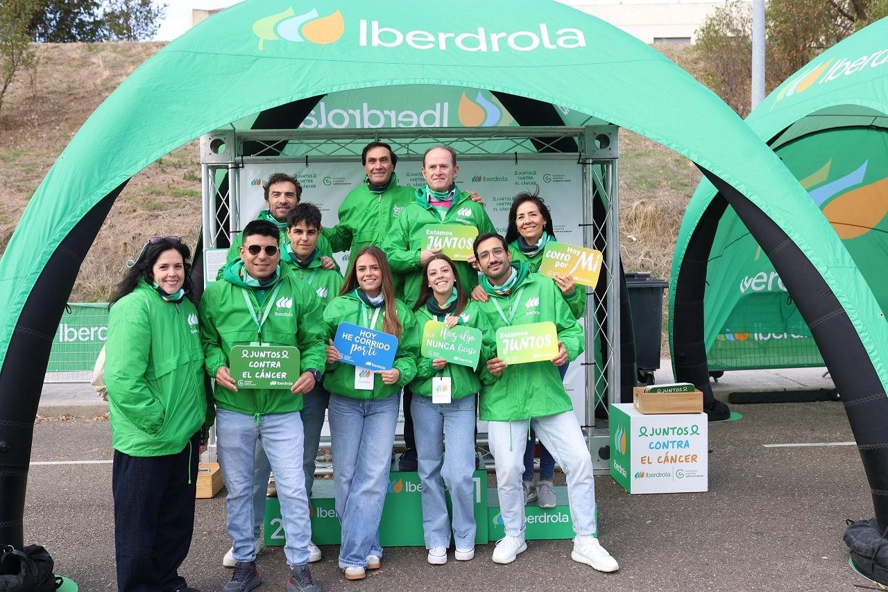 Voluntarios de Iberdrola España con camisetas verdes y carteles de apoyo a la lucha contra el cáncer en un evento solidario