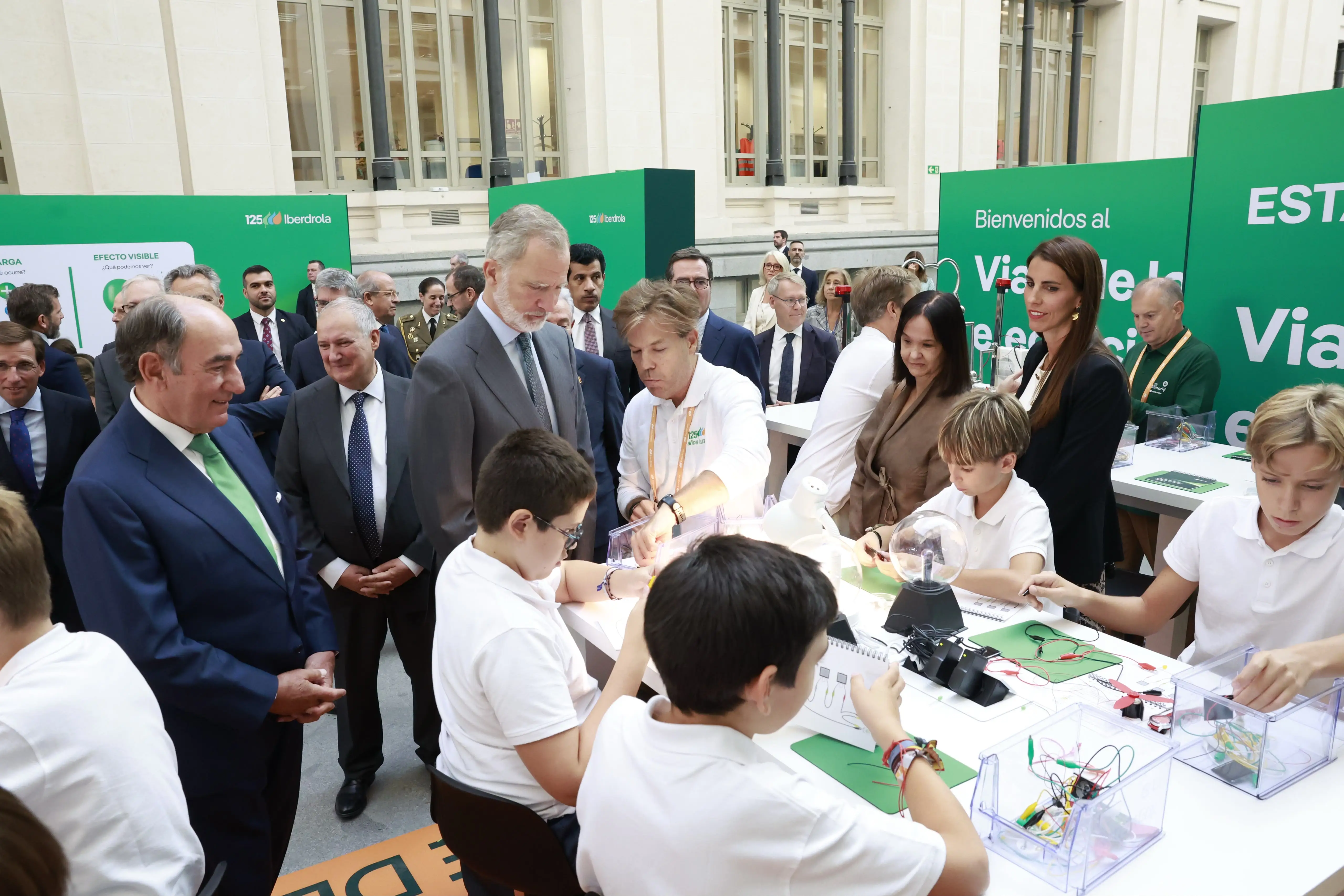Children conduct electrical experiments as institutional representatives observe the activity at an Iberdrola exhibition.