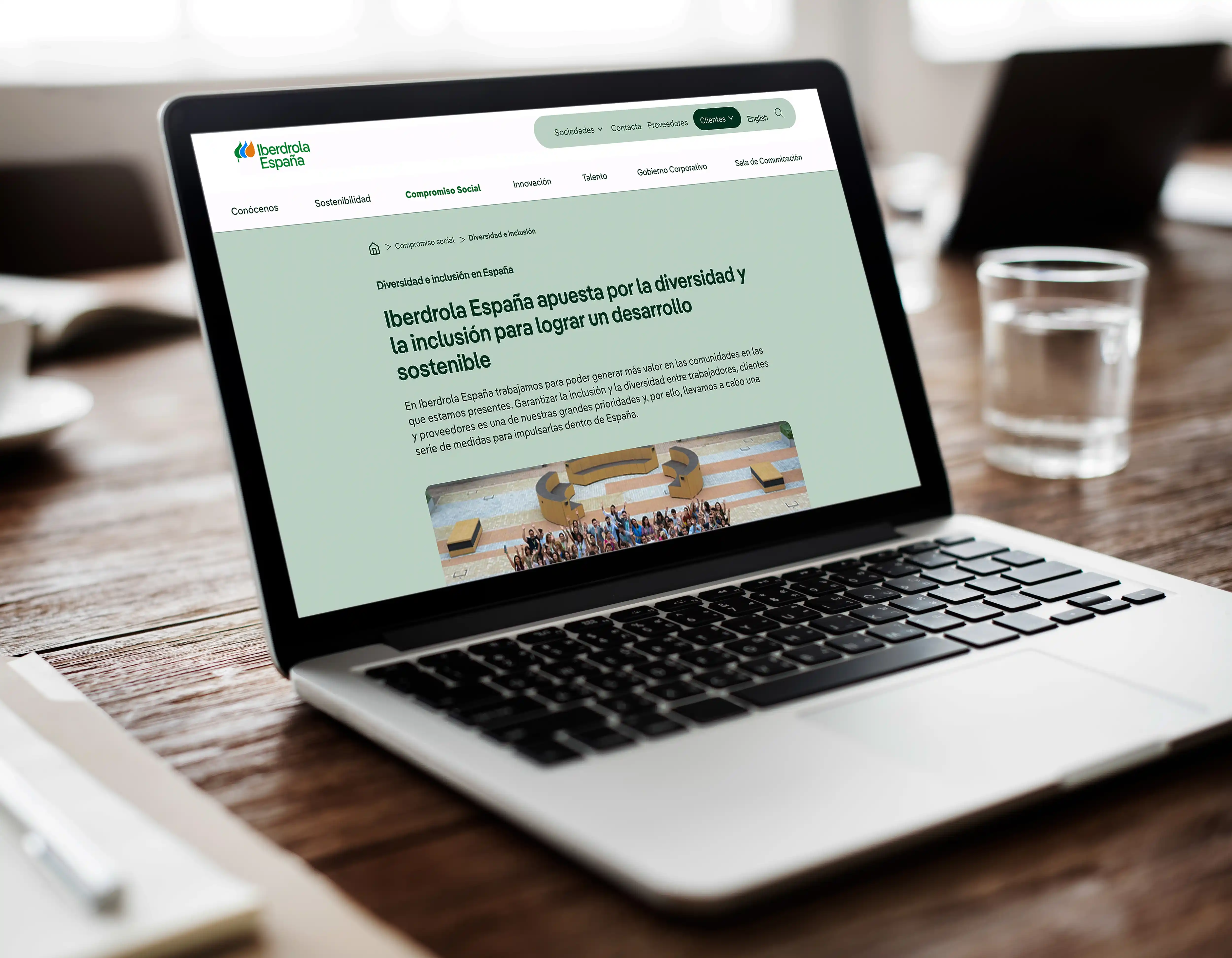 Laptop displaying Iberdrola España's "Diversity and Inclusion" webpage, with a coffee cup and water glass on the table.