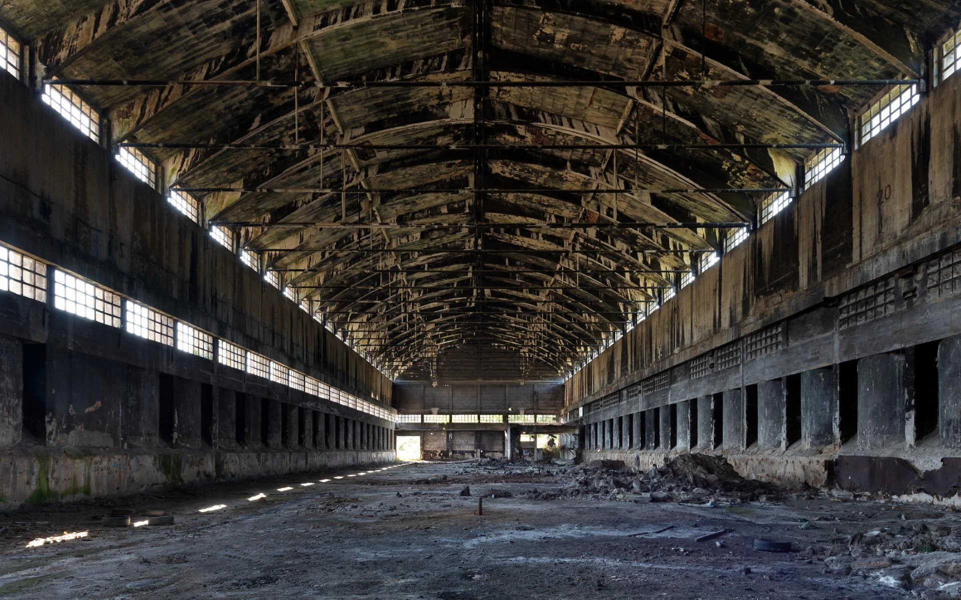 Current interior of an abandoned Nitrastur industrial building with a concrete structure and deteriorated roof.