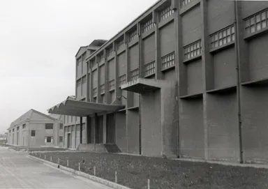 Historic façade of a Nitrastur industrial building with a concrete canopy above the loading area.