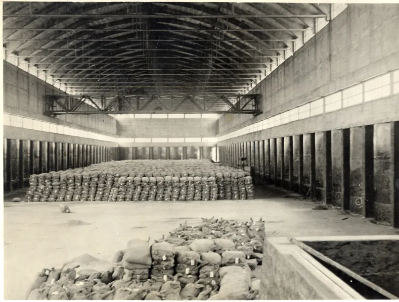 Historic interior of a Nitrastur industrial warehouse with stacked sacks of material.